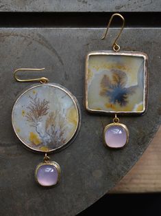 This elegant statement pair is a marriage between earthy golden dendritic agates and glowing lilac chalcedony. I love a good mismatched pair and I think these special stones sing gracefully together. One of a kind, these earrings are set in fine silver and 18k gold bezels on sterling silver backs with 18k gold ear hooks and connectors. Materials: dendritic agate, chalcedony, 18k yellow gold, .925 sterling silver, .999 fine silver Measures 70mm overall earring length. Send me a direct email at he Bold Statement Jewelry, Chalcedony Earrings, Nature Color Palette, Fine Silver Jewelry, Agate Earrings, Dendritic Agate, Metallic Accents, Fine Silver, Statement Jewelry