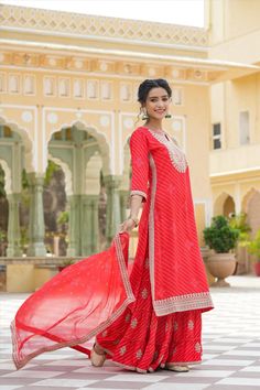 This Red Rayon Leheriya Embroidered Sharara Suit features a long kurta with Zari and Sequins embroidery accents on the yoke, sleeves, and hemline. The suit includes a coordinating sharara and a printed chiffon dupatta with an embroidered border for a unique, elegant look. Perfect for special occasions. Color: Red Top: Rayon Bottom: Rayon Dupatta: Chiffon Top Length: 46" Bottom Length: 41" Dupatta Size: 2.2 m Occasion: Festive Print-Pattern: Leheriya Ornamentation: Zari Shape: Straight Design Sid Semi-stitched Red Palazzo Set For Festivals, Festive Straight Kurta Palazzo Set For Traditional Ceremonies, Red Chanderi Sharara, Red Long Sleeve Chanderi Sharara, Festive Chikankari Embroidery Palazzo Set For Traditional Ceremonies, Semi-stitched Red Anarkali Set With Chikankari Embroidery, Red Chikankari Embroidered Sharara In Georgette, Red Georgette Sharara With Chikankari Embroidery, Red Chanderi Palazzo Set With Long Sleeves