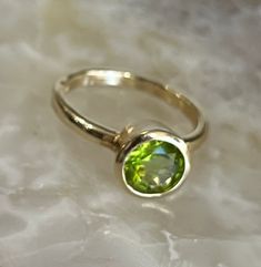 Genuine Peridot in 14K Solid Gold Ring Natural Peridot Natural Color Solid 14K Gold (not gold plated/ not gold filled) Round Stone 8 mm in Diameter. (9.7mm with the bezel) Weighs approximately 4.5 grams Band thickness is about 2.25mm Beautifully Faceted Bezel Set Made in La Jolla, California Ships from La Jolla, California FREE Shipping in USA Gold Rings With Smooth Bezel And Round Stone, Classic Green Bezel Set Birthstone Ring, Gold Oval Peridot Birthstone Ring, Classic Green Birthstone Ring With Bezel Setting, Yellow Gold Birthstone Ring With Smooth Bezel, Classic Green Ring With Smooth Bezel, Anniversary Yellow Gold Birthstone Ring With Smooth Bezel, Anniversary Green Ring With Smooth Bezel, Gold May Birthstone Ring With Round Stone