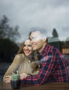 a man and woman sitting next to each other on a table with a cactus in front of them