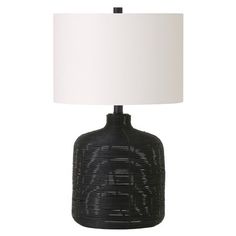 a black table lamp with a white shade on it's base and a light bulb in the middle