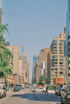 cars are driving down the street in front of tall buildings