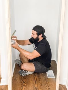 a man sitting on the floor using a paint roller