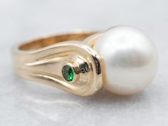 "This gorgeous modernist piece is crafted of polished yellow gold that is polished to a perfect shine. Utterly sleek, this vintage piece features a single, luscious pearl accented by sparkling diopside gemstones! Metal: 14K Yellow Gold Gem: Pearl Gem Measurements: 10.5 mm, Round Accents: 2 Diopside totaling .08 Carats Ring Size: 4.25 Marks: \"14K\" Stamped on the inside band SKU #: A27004 Each piece has been identified and graded by a Graduate Gemologist who has been certified by the Gemological Institute of America (GIA). We have six brick-and-mortar storefronts in Maine, Massachusetts, and New Hampshire and have been in business for over 25 years! Please visit our Shop's About Page or our website for more information about our jewelry. For questions about diamond grading, we recommend th Elegant Tsavorite Rings With Polished Finish, Elegant Green Pearl Ring With Gemstone, Elegant Green Gemstone Pearl Ring, Elegant Oval Pearl Ring With Birthstone, Elegant Oval Pearl Birthstone Ring, Ring Pearl, Gold Pearl Ring, Three Stone Ring, June Birthstone