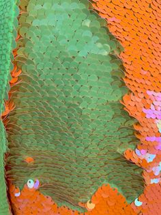 an orange and green piece of fabric with fish scales on it's back side