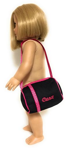 a doll with blonde hair is carrying a black and pink handbag that says dance