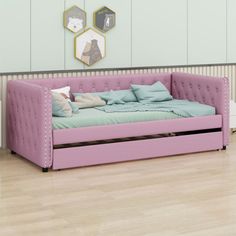 a pink daybed sitting on top of a hard wood floor next to a wall