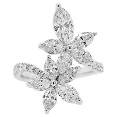 a white gold ring with diamonds in the center and leaves on each side, set against a