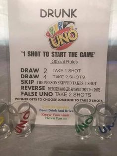 some glasses are on display in front of a sign that says drunk uno, shot to start the game