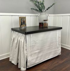 a white vase with flowers on top of a black and white striped table cloth draped over it