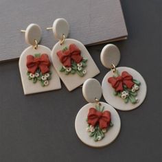 three pairs of earrings with bows on them sitting on top of a table next to a book