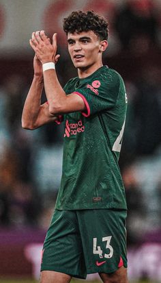 a soccer player is applauding the crowd with his hands up in celebration on the field