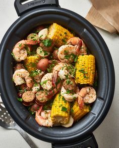 a skillet with shrimp, corn and potatoes