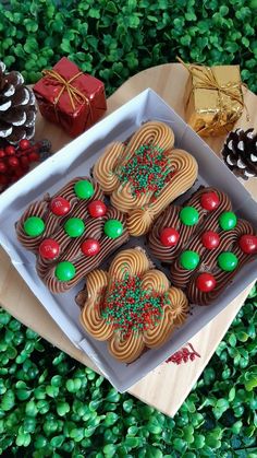 there are many decorated cookies in the box on the table next to pine cones and christmas decorations