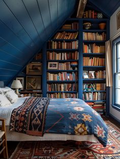 an attic bedroom with blue walls and bookshelves on the wall, along with a bed