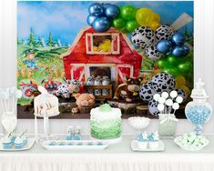 a table topped with cake and balloons next to a farm animal themed wall mural on the wall