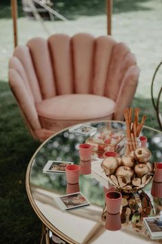 a glass table topped with vases next to a pink chair and other items on top of it