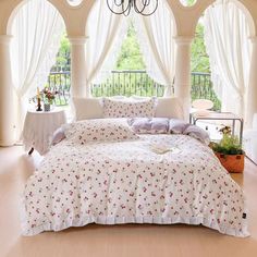 a bed with white sheets and pink flowers on it in front of a chandelier