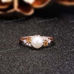 a pearl and diamond ring sitting on top of a table