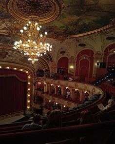 an auditorium with chandelier and people sitting on the seats in front of it