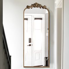 a mirror on the wall above a sink in a room with white walls and wood floors