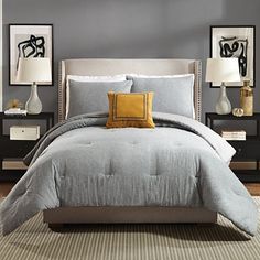 a bed in a bedroom with grey walls and yellow pillows on the pillowcases