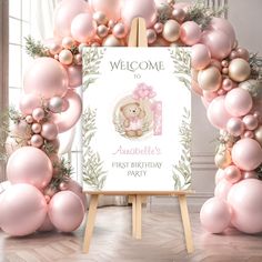 a welcome sign surrounded by pink balloons and greenery with a teddy bear on it