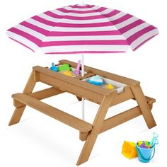 a wooden picnic table with an umbrella and sand tray on it's side, next to toys