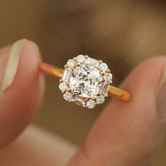 a close up of a person's hand holding an engagement ring