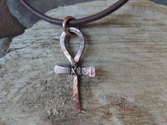 "This hammered and textured solid copper metalwork Ankh cross is a totally handmade piece of jewelry that can be for him or her! The cross has wire wrap around the center to add to its rustic look. A patina is added to the cross for a vintage weathered look. As a final touch, the cross is polished and sealed to avoid natural oxidation process. It measures about 1.7 inches x 0.8 inches / 4.3 cm x 2.1 cm. The pendant is hung on a 1/8\" / 2.5 mm genuine leather cord featuring a secure handmade hook Adjustable Brass Cross Jewelry, Adjustable Brass Cross-shaped Jewelry, Copper Cross Jewelry For Gifts, Handmade Bronze Crucifix Jewelry, Hammered Brown Jewelry For Gift, Brown Hammered Jewelry As A Gift, Brown Hammered Jewelry For Gift, Spiritual Hammered Cross Necklace, Artisan Hand Forged Cross Jewelry