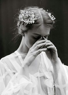 a black and white photo of a woman wearing a tiara with flowers in her hair