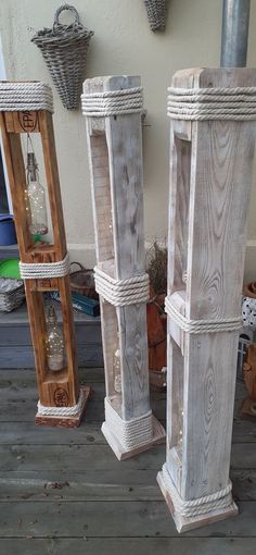 three tall white wooden vases sitting next to each other on a porch with rope wrapped around them