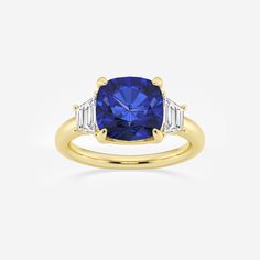 a yellow gold ring with an oval blue sapphire and two baguets on the side