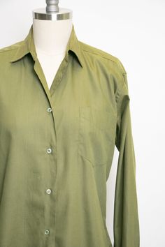 "Vintage 1950s ladies button down blouse in soft moss green cotton blend. Pointed collar. Relaxed yet feminine fit. Simple button front. Long sleeves that need cufflinks, not included. Unlined. Label: Adelaar man tailored shirt - Cotton + Darcon Fits like size: Medium Measurements: Bust: 38\" - 40\" pit tp pit Waist: 36\" Length: 22.5\" Shoulder to shoulder: 16\" Sleeve: 24\" Condition: Very good/good. Very minor under arm fade and a few faint marks that look oil based which didn't lift with soa Green Lapel Collar Shirt For Work, Khaki Collared Office Shirt, Khaki Collared Shirt For Office, Green Button-up Business Top, Collared Olive Shirt With Button Closure, Green Button-up Formal Shirt, Olive Collared Shirt With Button Closure, Semi-formal Green Button-up Shirt, Green Semi-formal Button-up Shirt