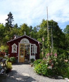 a small red building surrounded by lots of flowers