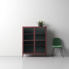 a green chair sitting next to a red bookcase on top of a white floor