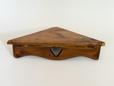 a wooden shelf with a heart shaped hole in the middle on a white wall background