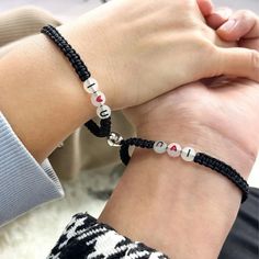 two people wearing bracelets that say love and one is holding the other's hand