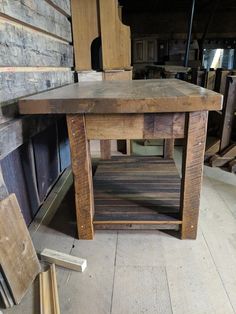 a wooden table sitting on top of a floor next to a pile of wood planks