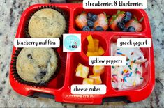 a red lunch box filled with fruit and muffins