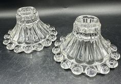 two clear glass candlesticks sitting on top of a black table next to each other