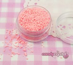 pink sprinkles are in a small jar on a checkered tablecloth