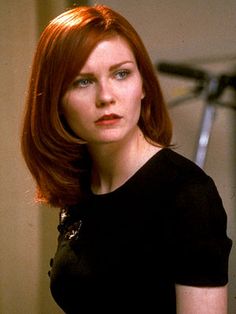 a woman with red hair is standing in front of a camera and looking off to the side