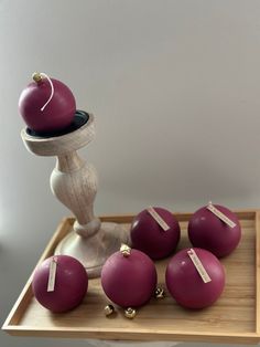 some red balls are sitting on a wooden tray with a white vase and other items