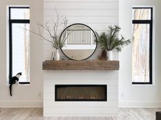 a white fireplace with a mirror and potted plants on the mantel above it