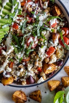 a bowl filled with vegetables and dressing on top of a white table next to other foods