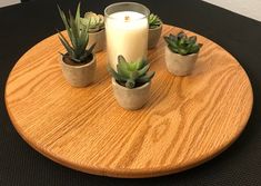 three succulents and a candle on a round table with a black surface