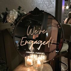 a mirror that says we're engaged with candles in front of it