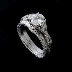 an intricately designed wedding ring set with a round diamond in the center and filigrees on each side