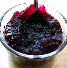 a glass bowl filled with blueberry sauce on top of a wooden table